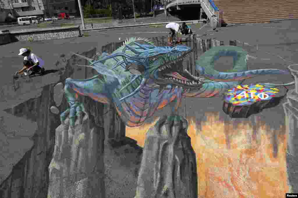 U.S. artist Tracy Lee Stum (L) and her assistants work on the &quot;Singing Dragon&quot; interactive 3-D street painting as they take part in the 4th Krasnoyarsk International Music Festival of the Asian-Pacific region in central Krasnoyarsk, Siberia, Russia. 