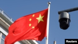 北京街頭飄揚的一面中國國旗旁的一個監控攝像頭。（2021年11月25日）