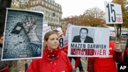 FILE - Lucie Morillon, head of research at French watchdog of Reporters Sans Frontieres (Reporters without Borders) holds a banner depicting Syrian human rights activist Mazen Darwish during a protest against violence in Syria, in Paris, Oct. 20, 2012.