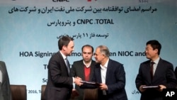 Head of the Middle East and North Africa division at Total, Stephane Michel, left, and managing director of the National Iranian Oil Company Ali Kardor, right, shake hands after signing documents in Tehran, Nov. 8, 2016. 