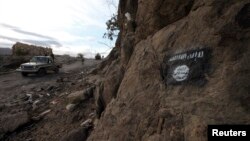 Un camion de rebelles chiites de Houthi patrouille alors qu'un drapeau d'Ansar al-Sharia est visible à flanc de colline sur une route proche de Rada au Yémen, le 22 novembre 2014. 