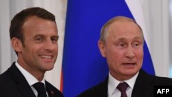 Le président russe Vladimir Poutine serre la main de son homologue français Emmanuel Macron à l'issue d'une conférence de presse conjointe au palais Konstantin à Strelna, près de Saint-Pétersbourg, le 24 mai 2018. 