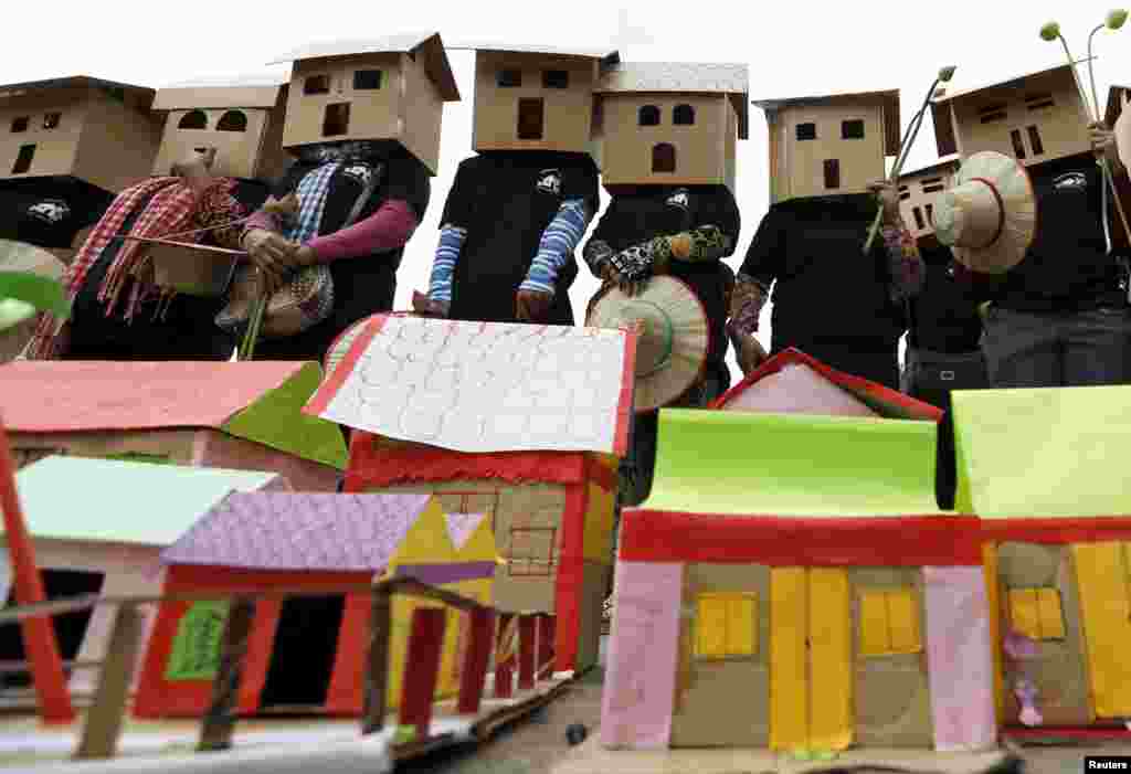 People wear house models during a march held on World Habitat Day in central Phnom Penh, Cambodia. Former residents of Boeung Kak lake, Borei Keila neighbourhood and other communities affected by private corporation developers called on the Cambodian government to stop evicting them from their homes, local media reports say.