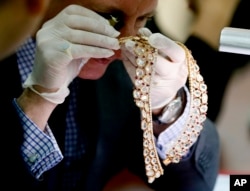 FILE - Christie's auction house appraiser David Warren examines a set of jewelry from Roumeliotes Collection, one of three sets of the Marcos Jewelry Collection, during appraisal at the Central Bank of the Philippines, Nov. 24, 2015 in Manila, Philippines.