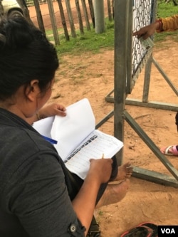 A member of Cambodia’s ruling party uses an illustrated list to check voters at a polling station in Samaki Sopheap Primary School in Kampong Kdei Commune, Chikreng District, Siem Reap Province. (Thida Win/VOA Khmer)