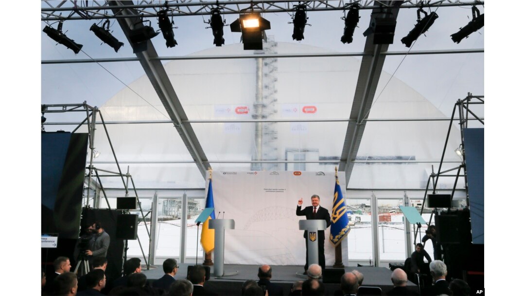 Ukrainian President Petro Poroshenko speaks at the unveiling ceremony of a new shelter, in the back, installed over the exploded reactor at the Chernobyl nuclear plant, Chernobyl, Ukraine, Nov. 29, 2016.