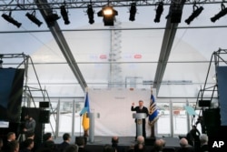 Ukrainian President Petro Poroshenko speaks at the unveiling ceremony of a new shelter, in the back, installed over the exploded reactor at the Chernobyl nuclear plant, Chernobyl, Ukraine, Nov. 29, 2016.