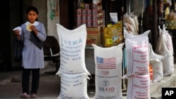 (File) A Palestinian girl walks past sacks of flour food aid from the United Nations and USAID at the Shatie refugee camp in Gaza City.