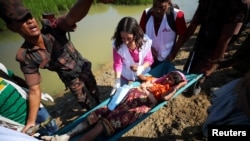 A pregnant Rohingya refugee who is in labor, is brought to a medical center on a stretcher after crossing the Bangladesh-Myanmar border in Palong Khali, near Cox's Bazar, Bangladesh, Nov. 3, 2017.