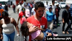 A Central American migrant traveling with the annual migrant Stations of the Cross caravan carries a little girl during a march for migrants' rights and protest against the policies of U.S. President Donald Trump, in Hermosillo, Mexico, Monday, April 23, 2018. (AP Photo/Luis Gutierrez)