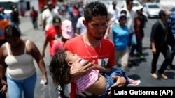 Un migrant d'Amérique centrale avec une petite fille lors d'une marche pour les droits des migrants et contre la politique du président américain Donald Trump, à Hermosillo, au Mexique, le 23 avril 2018.