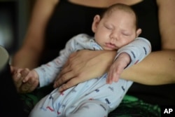 FILE - Two-month-old Inti Perez, diagnosed with microcephaly linked to the mosquito-borne Zika virus, is cradled by his mother, in Bayamon, Puerto Rico.