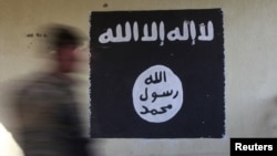 FILE - A soldier walks past a black flag commonly used by Islamic State militants. Pakistani officials acknowledged that at least one IS flag was recently displayed on a billboard in Islamabad, but some sources told VOA other IS flags were seen in other parts of city.