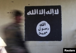 FILE - A soldier walks past a black flag commonly used by Islamic State militants.