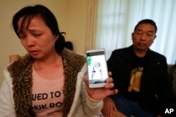 Ronggao Zhang, and her husband, display a photo of their missing daughter Yingying Zhang, a University of Illinois student, in Urbana, Ill., Wednesday, Nov. 1, 2017. (AP Photo/Michael Conroy)