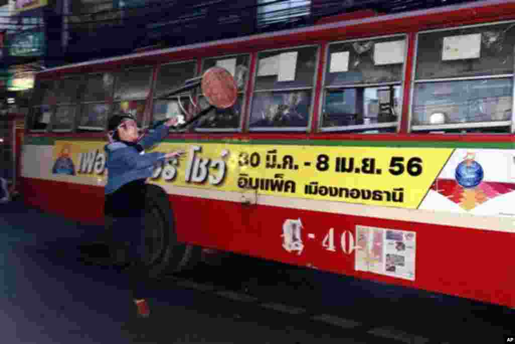 An anti-government protester attacks people they suspected of supporting the current Thai government on the bus in Bangkok,Thailand Saturday, Nov. 30, 2013. A mob of anti-government protesters smashed the windows of a moving Bangkok bus Saturday in the fi