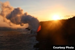 A wider view of the lava entering the ocean at sunset.