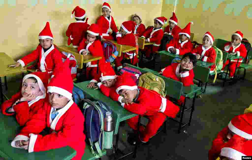 Children dressed in Santa Claus costumes sit inside a classroom before participating in Christmas celebrations at a school in Chandigarh, India.