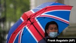 Un journaliste portant un masque pour se protéger du coronavirus, non loin du 10 Downing Street à Londres, mardi 28 avril 2020. (AP Photo / Frank Augstein)