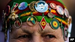 FILE - A woman wears Kurdish symbols and a sticker with a portrait of Abdullah Ocalan, the jailed leader of the rebel Kurdistan Workers' Party, or PKK, as she attends a protest of the visit of Turkish President Recep Tayyip Erdogan in Berlin, Germany.