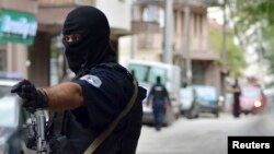 Police in Kosovo arrested 15 people Wednesday in the second major operation in weeks to stem the flow of young ethnic Albanians joining Islamist fighters in Iraq and Syria, a police source said. A masked police officer stands guard in front of a court in 