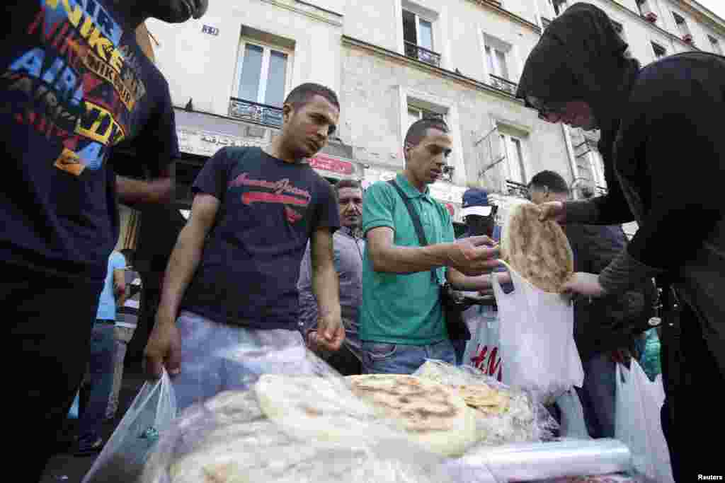 Seorang pedagang menjual roti tradisional di sebuah jalan di Paris (10/7). (Reuters/Youssef Boudlal)