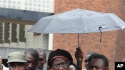 Munyaradzi Gwisa, centre, talks to media as he leaves the magistrates courts in Harare, Wednesday, March 21, 2012. Gwisai, a human rights activist and five others were found guilty and made to pay a fine of $500 each and perform community service, for "co