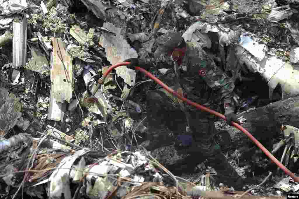 A rescue worker makes his way through the debris at an air force plane crash site near Nadee village, Xiang Khouang province, Laos, May 17, 2014.