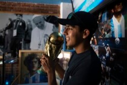 Raul Martinez, seorang pengunjung, berpose dengan replika Piala Dunia FIFA, di Gereja Maradona di San Andres Cholula, negara bagian Puebla, Meksiko, Minggu, 18 Juli 2021. (AP)