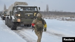A service member of the Ukrainian Armed Forces runs near self-propelled multiple rocket launcher systems during drills in the Kherson region, Ukraine, in this handout picture released Feb. 1, 2022. 