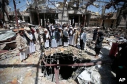 FILE- Members of the Higher Council for Civilian Community Organization inspect a destroyed funeral hall as they protest against a deadly Saudi-led airstrike six days earlier in Sanaa, Yemen, Oct. 13, 2016.