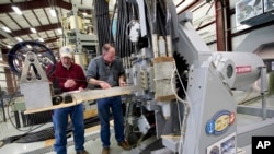 In this Thursday, Feb. 23, 2012, file photo provided by the U.S. Navy, Gary Bass, left, and Jim Poyner, from the Naval Surface Warfare Center, Dahlgren Division, take measurements after a successful test firing of an electromagnetic railgun prototype launcher.