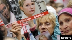 Supporters of Ukraine's jailed former Prime Minister Yulia Tymoshenko hold up posters of Tymoshenko, during a rally near the high court building in Kiev, August 29, 2012.