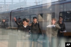FILE - One Syrian and five Afghan boys wave on the platform of the Calais train station, northern France, as they leave for Britain, Oct. 13, 2016.
