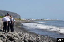 FILE - Police officers inspect metallic debris found on a beach in Saint-Denis on the French Reunion Island in the Indian Ocean on Aug. 2, 2015, close to where a Boeing 777 wing part believed to belong to missing flight MH370 washed up.