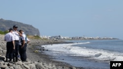 Polisi memeriksa potongan logam yang ditemukan di pantai di Saint-Denis, Pulau Reunion di Samudera Hindia (2/8). (AFP/Richard Bouhet)