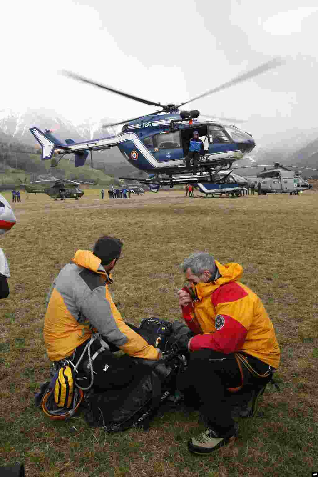 Rescue workers watch a rescue helicopter taking off from Seyne-les-Alpes, French Alps, March 24, 2015. 