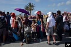 People wait in line while U.S. Air force units prepare to evacuate several hundred American citizens from Princes Juliana International Airport after the passage of Hurricane Irma, in St. Martin, Sept. 11, 2017.