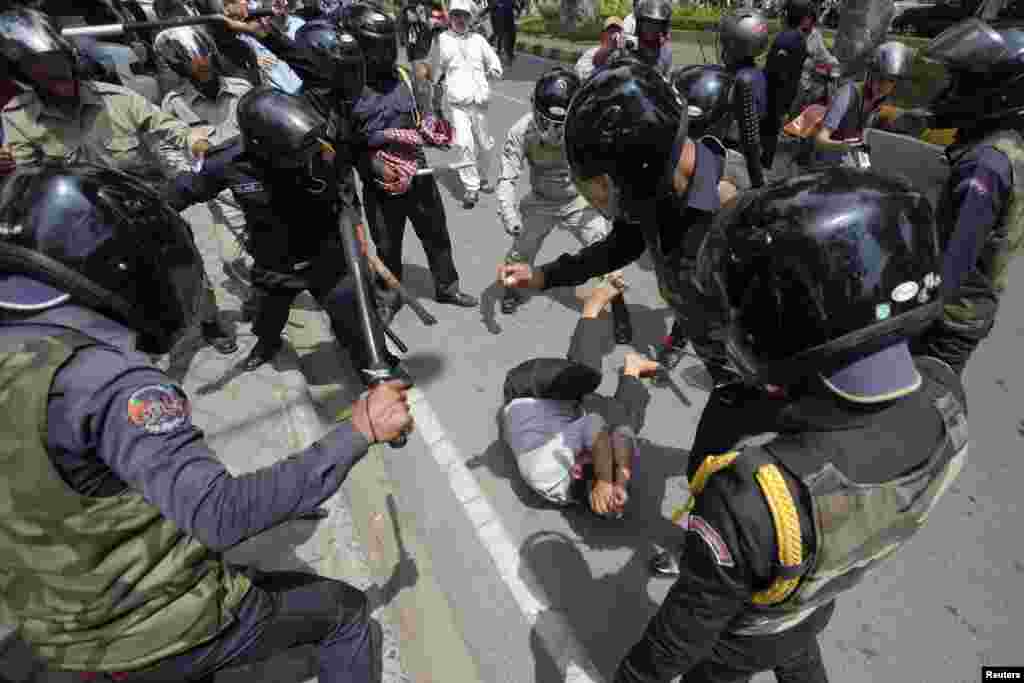 A man tries to protects himself as security forces beat him during the International Workers&#39; Day rally at Freedom Park in Phnom Penh, Cambodia. Authorities broke up a protest of garment workers and opposition party supporters who rallied to celebrate the Labor Day despite the government&#39;s ban on public assemblies.