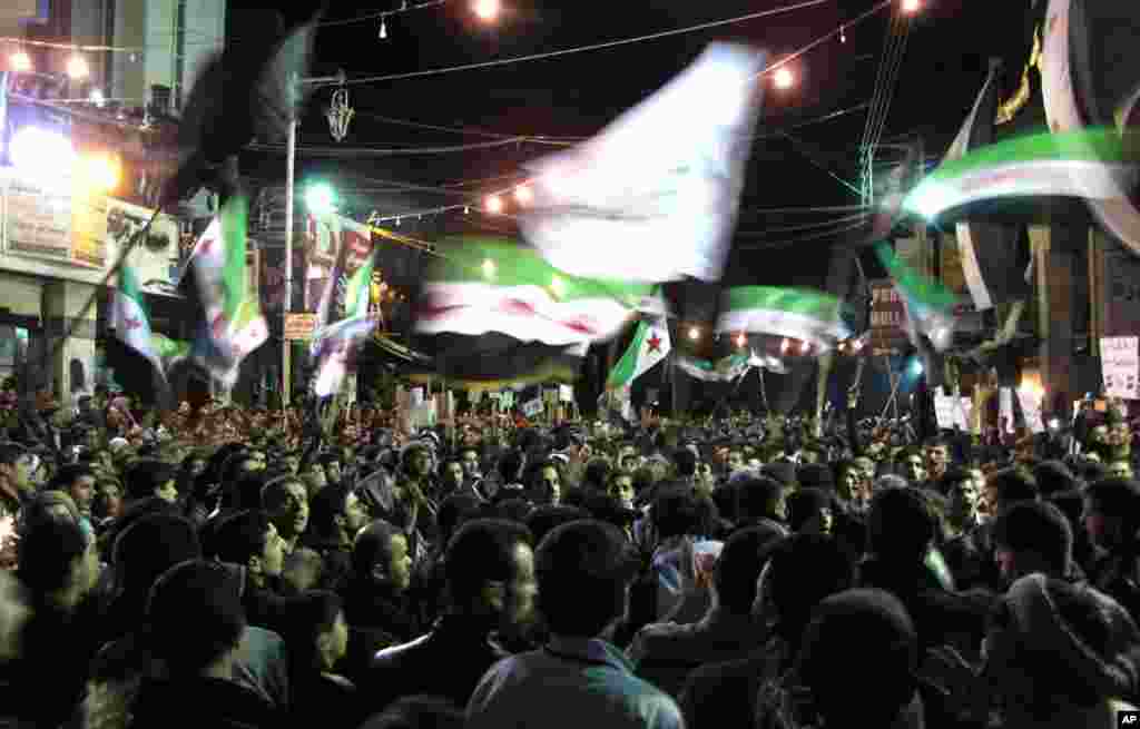 Syrians wave revolutionary flags at a night protest against President Bashar Assad in Damascus, April 2, 2012. (AP)