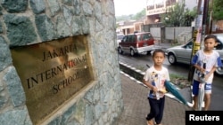 Dua anak laki-laki melewati bagian depan Jakarta International School.