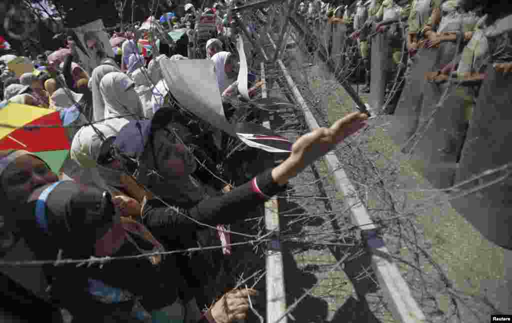 Female members of the Muslim Brotherhood and supporters of ousted Egyptian President Mohamed Morsi shout slogans at a barbed wire fence near the Defense Ministry in Cairo, July 21, 2013.