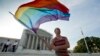 Gay rights advocate Vin Testa waves a rainbow flag in front of the Supreme Court at sun up in Washington, June 26, 2013. 