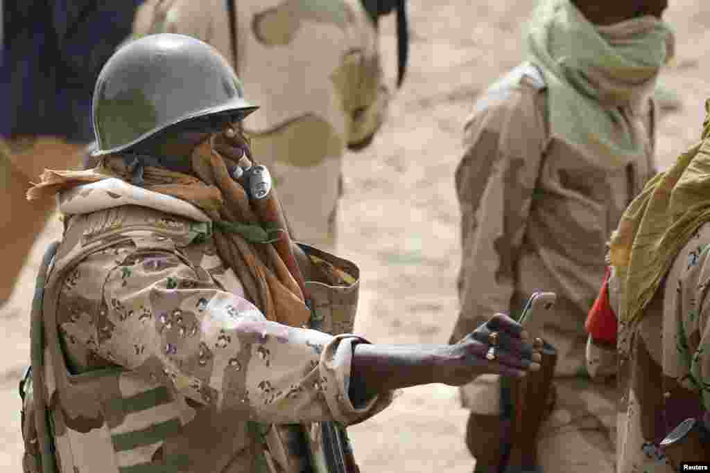 Un soldat nigérien couvre son visage tout en prenant une photo d&#39;un charnier à Damasak, ville récemment reprise de Bokok Haram, au Nigeria, le 20 Mars 2015.