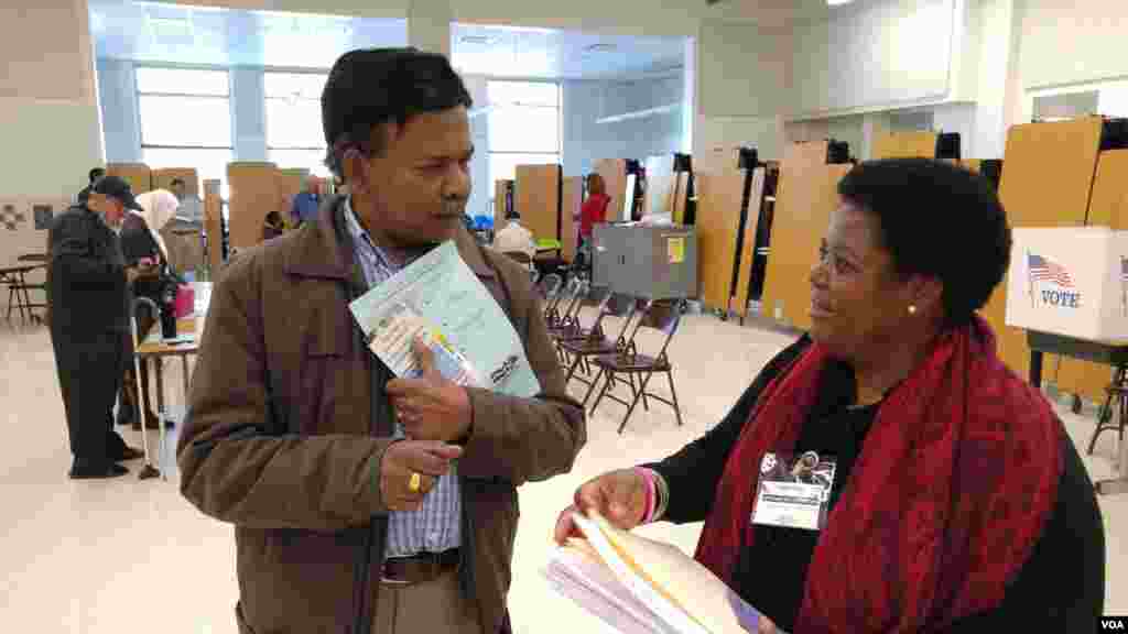 Virginia voter gets election materials from polling station worker before voting in US presidential election, Nov. 8, 2016. (Photo: D. Block / VOA) 