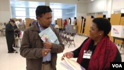 Virginia voter gets election materials from polling station worker before voting in US presidential election, Nov. 8, 2016. (Photo: D. Block / VOA)