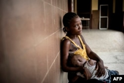 Rachel Sakie (16) and her daughter Isaatu (15 months) await for consultation at the Star of the Sun Health Center in the Monrovia township of West Point, Liberia, April 29, 2016.