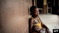 Rachel Sakie (16) and her daughter Isaatu (15 months) await for consultation at the Star of the Sun Health Center in the Monrovia township of West Point, Liberia, April 29, 2016.