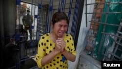 A garment worker cries as factory guards are seen in the background after clashes broke out during a protest in Phnom Penh, Jan. 3, 2014. 