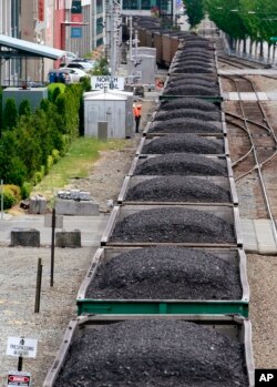 FILE - A train hauling coal runs between office buildings, condos and the downtown waterfront in Seattle, Wash. Scientific consensus holds that the emission of greenhouse gases from the burning of fossil fuels is the main cause of global warming.